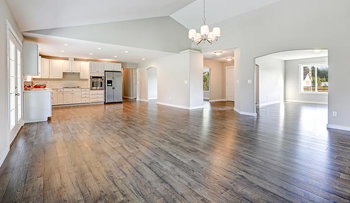 An open living space with freshly refinished hardwood floors showing a smooth, uniform, and restored surface.