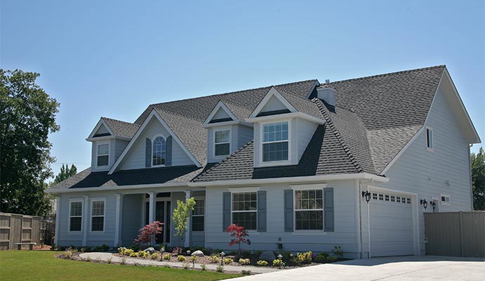A light blue two-story house with white trim, featuring multiple gables and dormer windows, a dark grey shingle roof