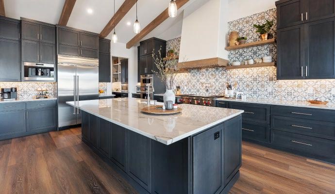 A spacious, modern kitchen featuring dark navy cabinetry, white marble countertops, a large central island