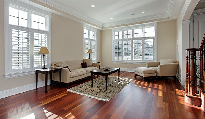 A pristine living room with polished hardwood floors, white shutters, and professional interior painting.