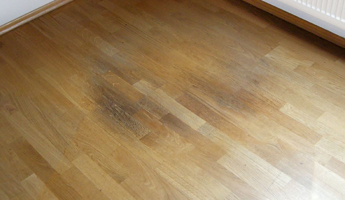 Damaged wooden floor with a large dark stain