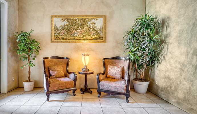A cozy sitting room featuring two classic wingback chairs, a small accent table with a lamp