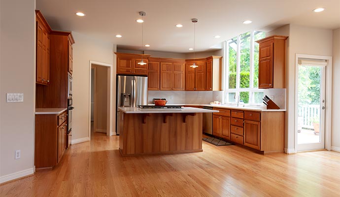 A large kitchen with traditional honey-colored wood cabinets, a central island with a white countertop and built-in stovetop