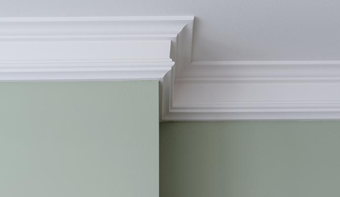 White crown molding at intersection of light green wall and white ceiling