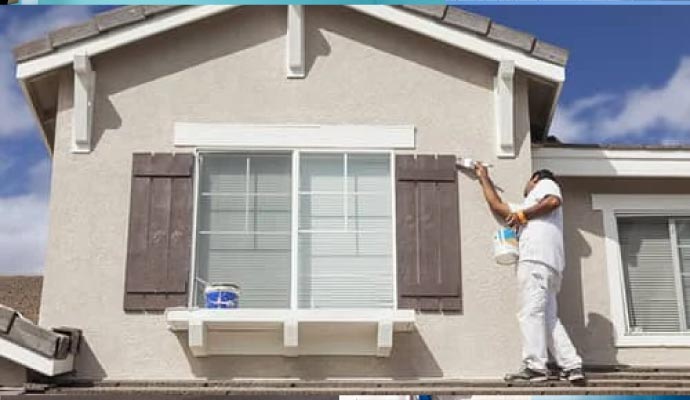 Professional worker painting exterior of a residential building
