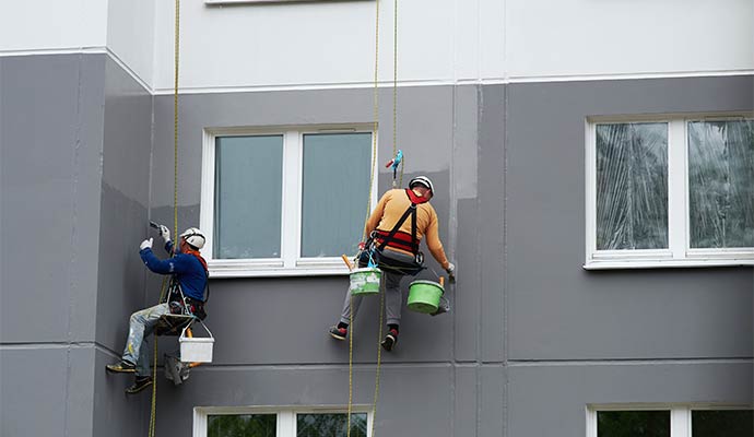 Couple of professional workers painting exterior wall