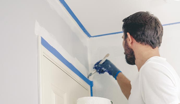 Professional painter painting around door trim