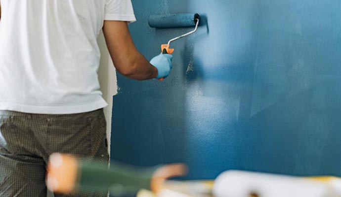 Professional painter applying teal stain wall paint