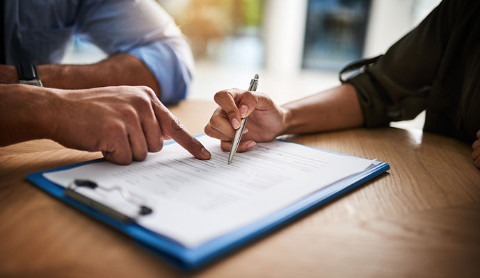 Close-up of a person signing a insurance document