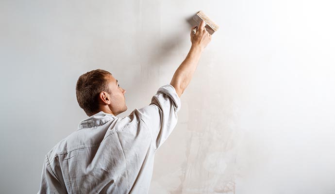 man painting wall with roller